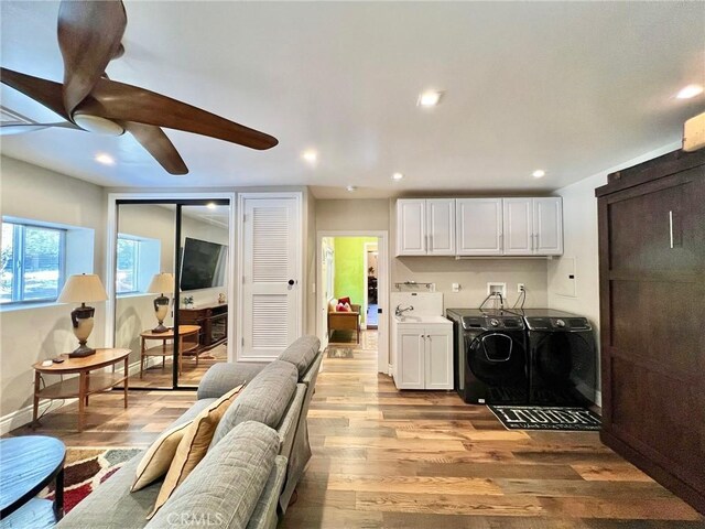 kitchen featuring light hardwood / wood-style floors, white cabinetry, washer and clothes dryer, and sink