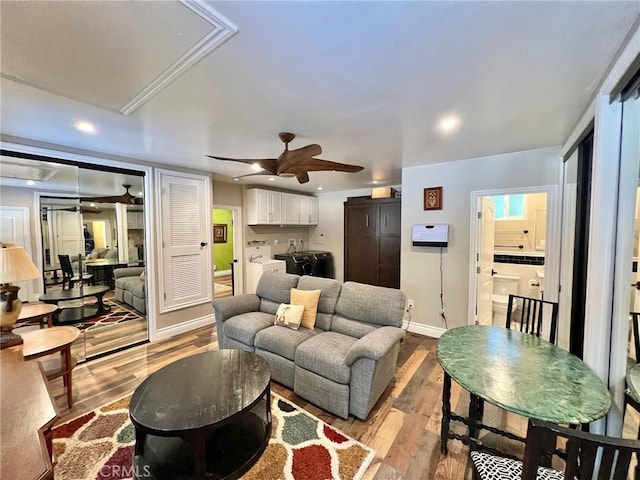 living room featuring ceiling fan, light wood-type flooring, and washer / clothes dryer