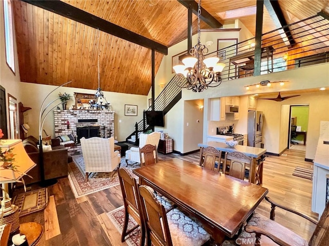 dining space featuring beamed ceiling, a fireplace, hardwood / wood-style floors, and high vaulted ceiling