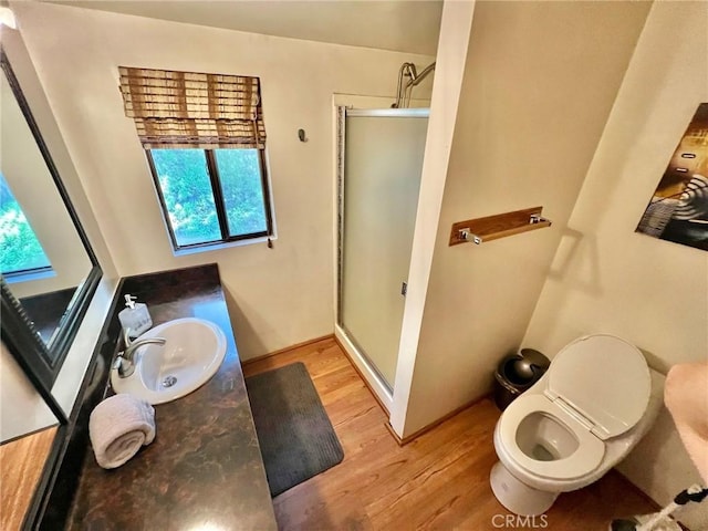 bathroom with a wealth of natural light, a shower with door, vanity, and hardwood / wood-style floors