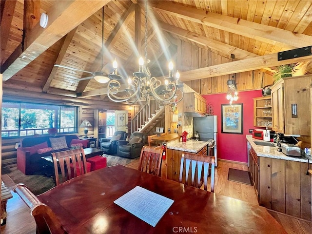 dining area featuring ceiling fan with notable chandelier, vaulted ceiling with beams, light hardwood / wood-style floors, and wood ceiling