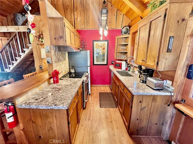 kitchen with electric range, sink, light stone countertops, and decorative light fixtures