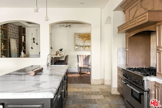 kitchen with dark wood-type flooring, tasteful backsplash, range with two ovens, light stone counters, and sink