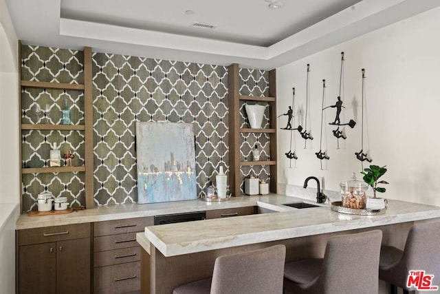 bar with sink and a tray ceiling