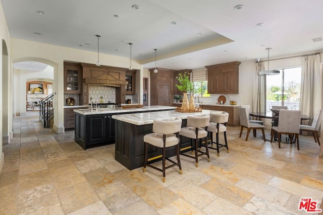 kitchen featuring light tile patterned floors, sink, pendant lighting, and an island with sink