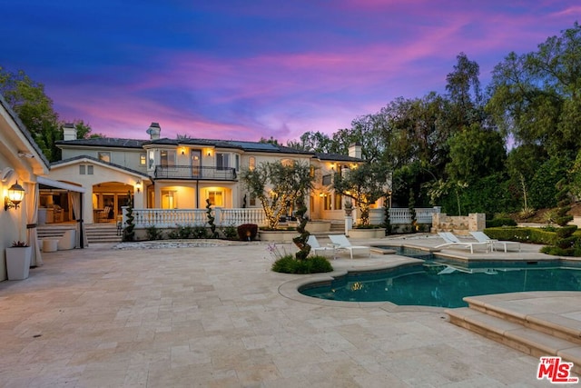 pool at dusk with a patio