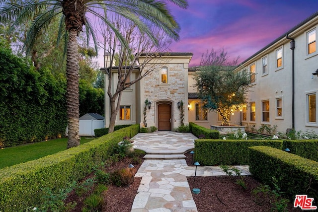 mediterranean / spanish house featuring a lawn and a storage unit