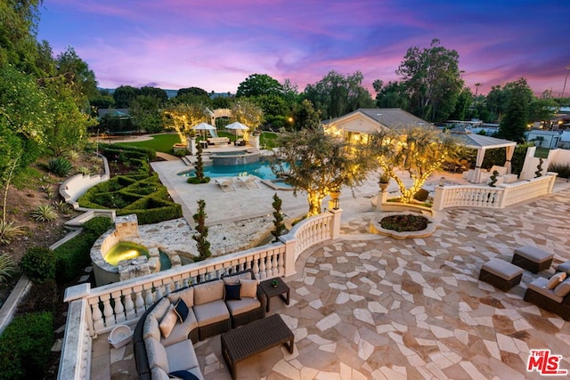 pool at dusk with a patio and an outdoor hangout area