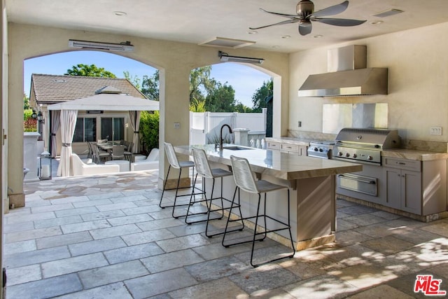 view of patio with ceiling fan, an outdoor wet bar, an outdoor kitchen, and a grill