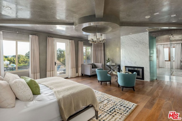 bedroom with a fireplace, a notable chandelier, lofted ceiling, and wood-type flooring