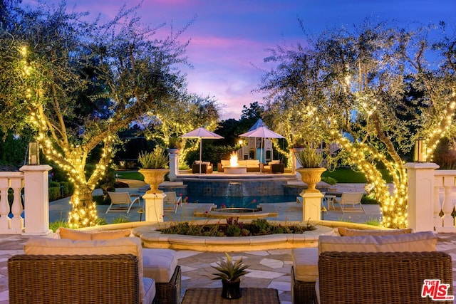 pool at dusk featuring a patio