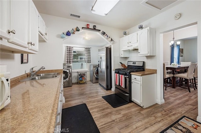 kitchen featuring pendant lighting, sink, white cabinetry, gas stove, and stainless steel fridge with ice dispenser