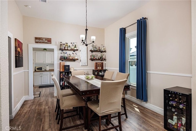 dining space featuring a notable chandelier, dark hardwood / wood-style flooring, and beverage cooler