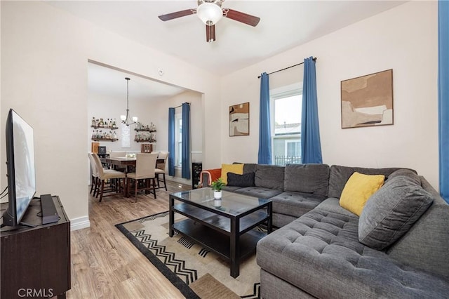 living room with wood-type flooring and ceiling fan with notable chandelier