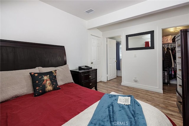 bedroom featuring a walk in closet, light hardwood / wood-style floors, and a closet