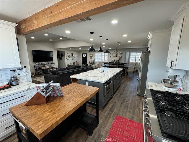 kitchen with white cabinets, decorative backsplash, light stone countertops, appliances with stainless steel finishes, and a kitchen island