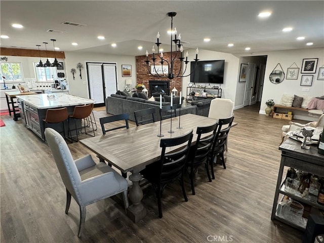 dining room featuring hardwood / wood-style floors, an inviting chandelier, and a brick fireplace