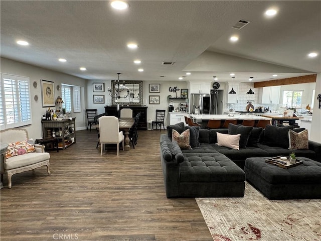 living room with plenty of natural light, dark hardwood / wood-style floors, a chandelier, and vaulted ceiling