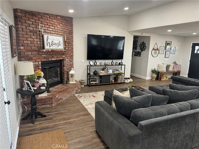 living room featuring hardwood / wood-style floors, vaulted ceiling, a brick fireplace, and plenty of natural light