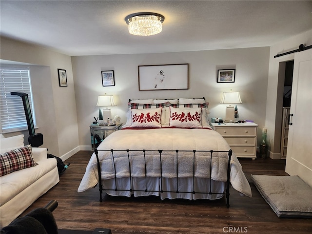 bedroom featuring a barn door and dark wood-type flooring