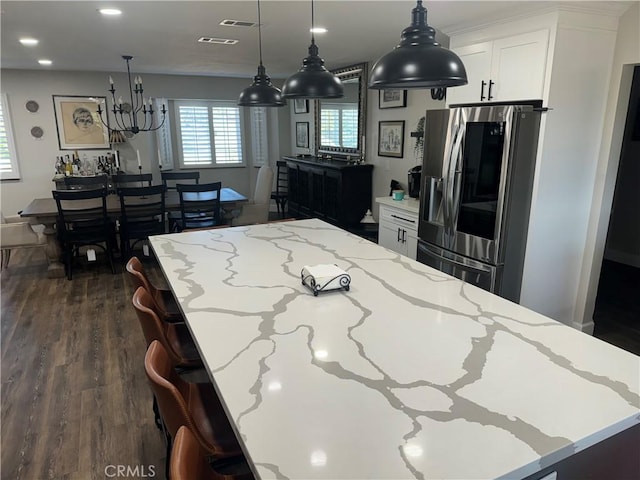 kitchen featuring stainless steel fridge with ice dispenser, light stone counters, dark hardwood / wood-style floors, pendant lighting, and white cabinets