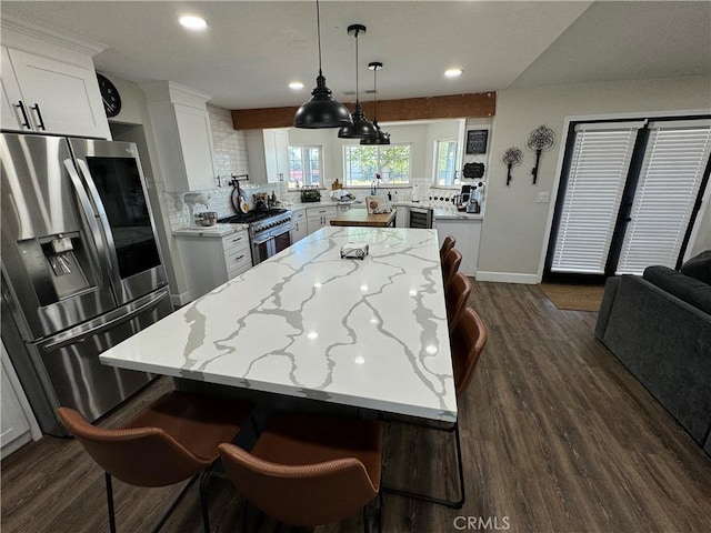 kitchen with white cabinets, dark hardwood / wood-style floors, a center island, and appliances with stainless steel finishes