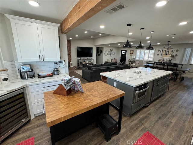 kitchen with a center island, white cabinetry, and beverage cooler