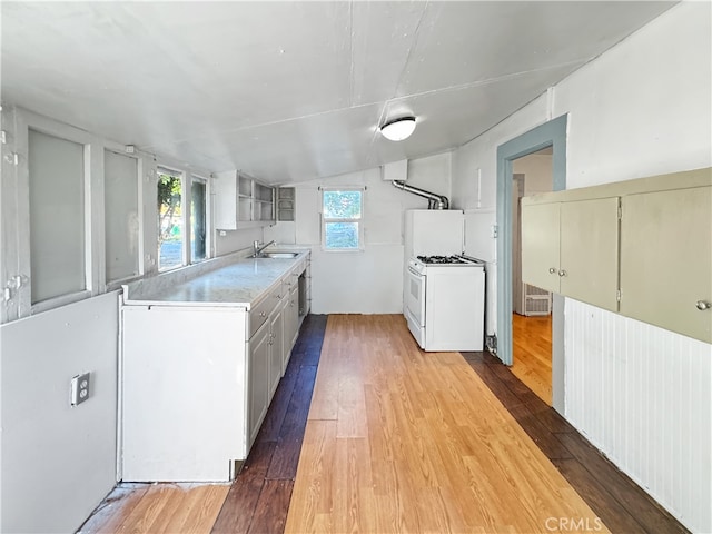 kitchen with white cabinets, white range with gas stovetop, wood-type flooring, vaulted ceiling, and sink