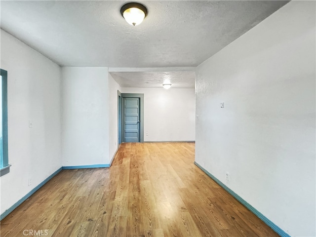 empty room with a textured ceiling and light wood-type flooring