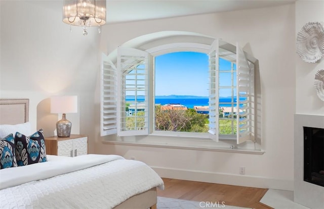 bedroom with hardwood / wood-style floors, an inviting chandelier, and multiple windows