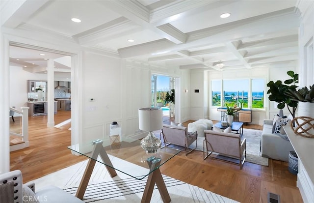 living room featuring hardwood / wood-style floors, crown molding, coffered ceiling, and beam ceiling