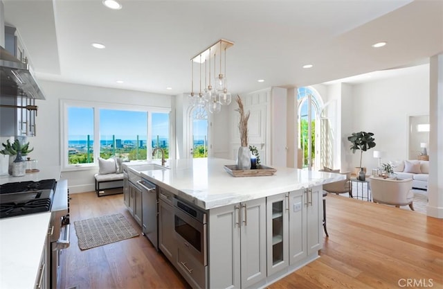 kitchen featuring light wood-type flooring, gray cabinetry, sink, pendant lighting, and a kitchen island