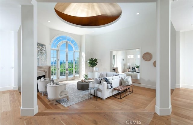 interior space with light wood-type flooring, a towering ceiling, and a tray ceiling