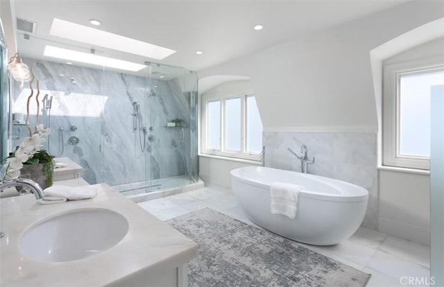 bathroom featuring vanity, separate shower and tub, tile walls, and a skylight