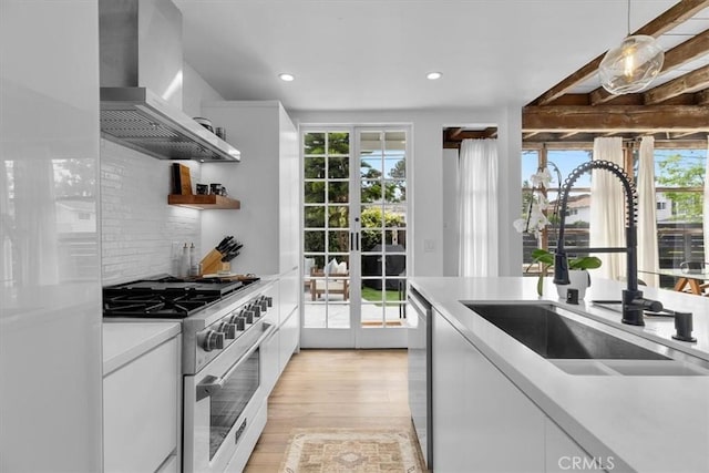 kitchen featuring white cabinets, appliances with stainless steel finishes, extractor fan, decorative light fixtures, and sink