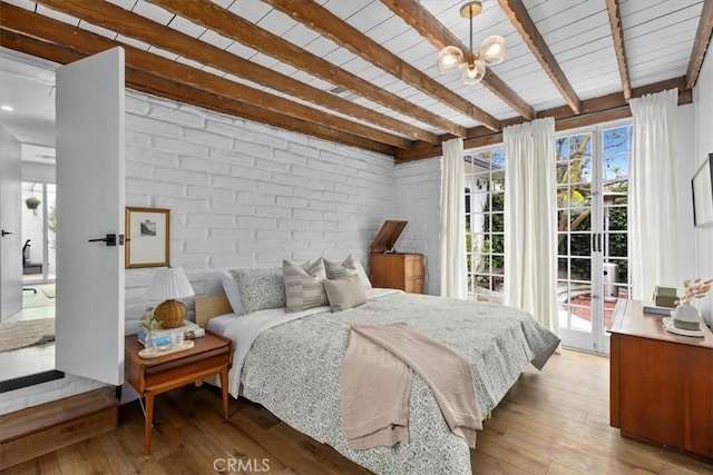 bedroom featuring brick wall, access to exterior, a chandelier, light hardwood / wood-style flooring, and beam ceiling