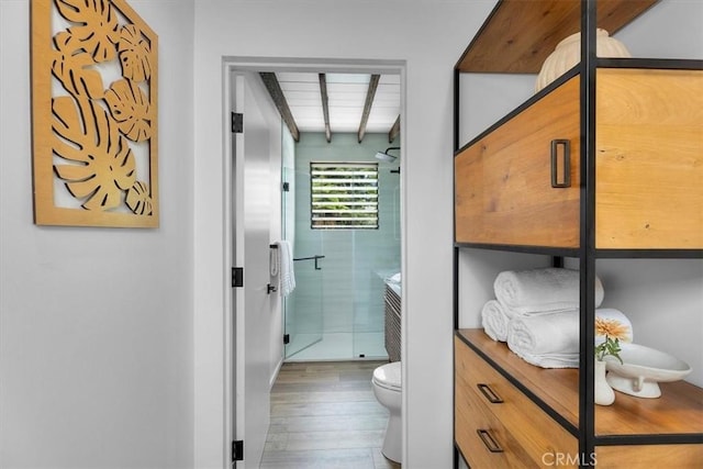 bathroom featuring toilet, beam ceiling, walk in shower, and hardwood / wood-style floors