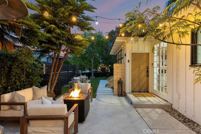 patio terrace at dusk featuring an outdoor living space with a fire pit