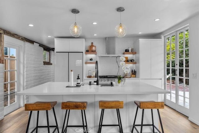 kitchen with decorative light fixtures, white cabinets, white refrigerator, and wall chimney exhaust hood