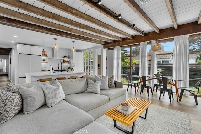 living room with beam ceiling, light hardwood / wood-style flooring, and sink