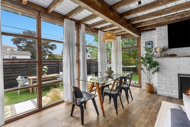 sunroom / solarium featuring beam ceiling and a stone fireplace