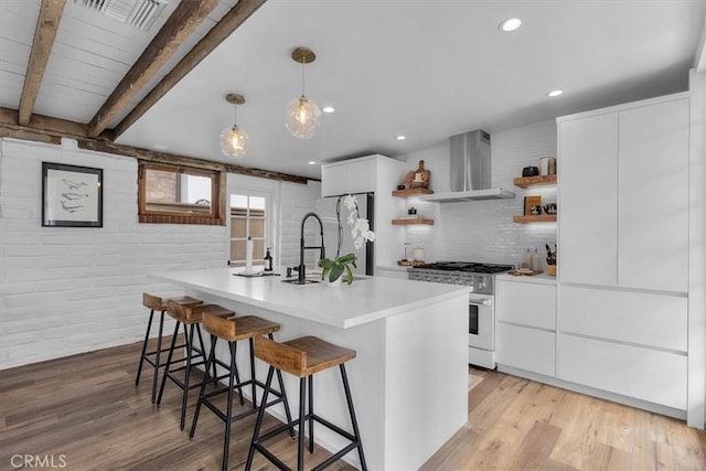 kitchen featuring appliances with stainless steel finishes, wall chimney exhaust hood, beamed ceiling, and white cabinetry