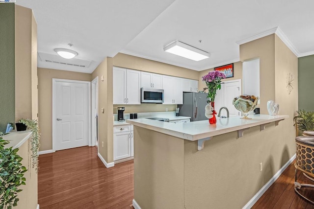 kitchen featuring dark hardwood / wood-style floors, stainless steel appliances, a breakfast bar, and white cabinetry