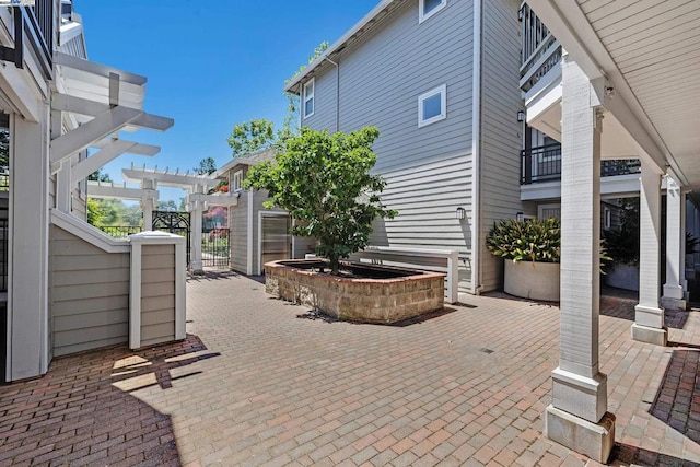 view of patio featuring a pergola and a balcony