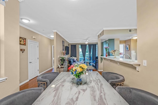 dining space featuring sink, ornamental molding, wood-type flooring, and ceiling fan