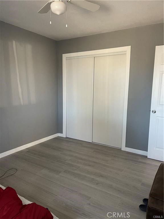 unfurnished bedroom featuring ceiling fan, a closet, and wood-type flooring