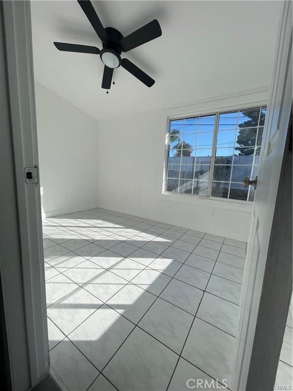 tiled spare room with ceiling fan