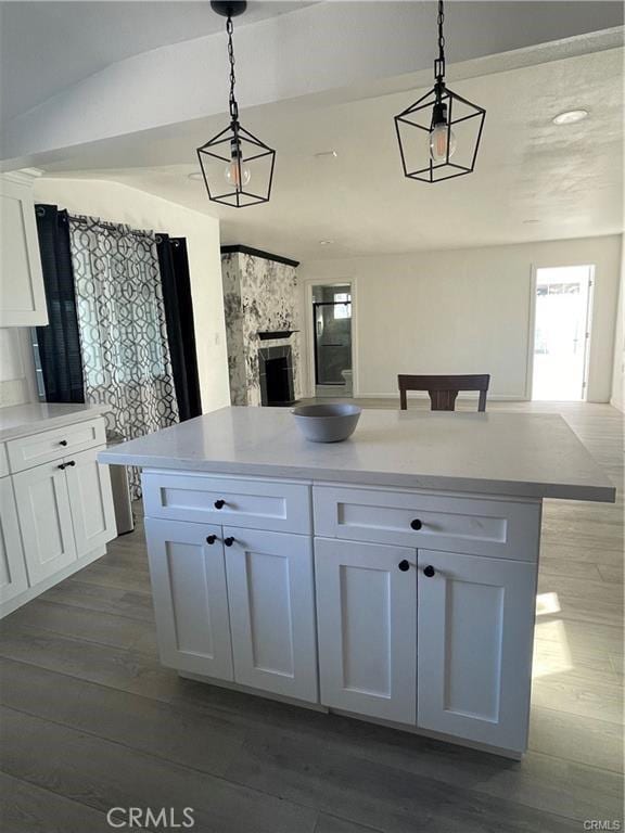 kitchen with a center island, decorative light fixtures, a fireplace, white cabinets, and hardwood / wood-style flooring