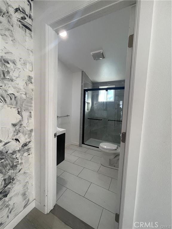 bathroom featuring tile patterned floors, toilet, vanity, and walk in shower