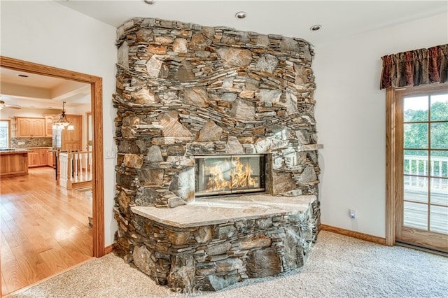 details featuring carpet floors, ceiling fan, backsplash, and a stone fireplace